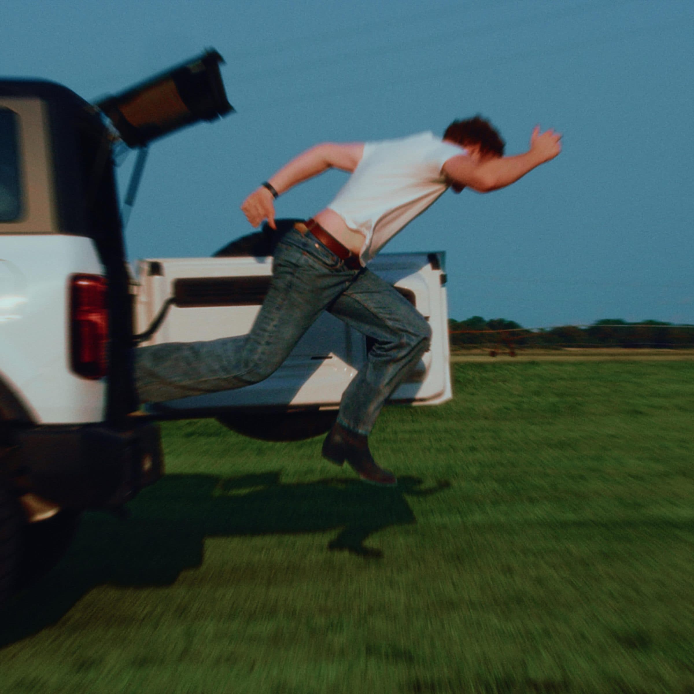 Solomon Post leaping from a Bronco in an open field at blue hour